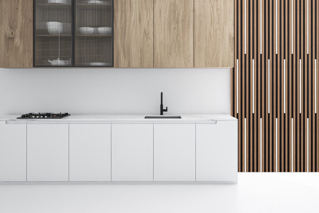 Interior of spacious kitchen with white walls and floor, white countertops with built in sink and cooker and wooden cupboards. 3d rendering